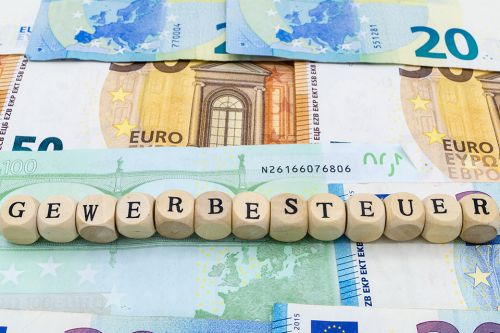 Aufschrift Gewerbesteuer auf Holzwürfel vor Geldscheinen